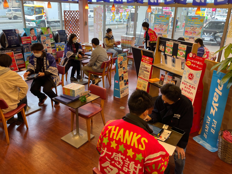 ガソリンスタンド内のイベントで、店内で複数のお客様がイベントスタッフから接客を受けている様子